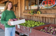 Pommes sur un stand de fruits avec une consommatrice tenant une boîte de pommes